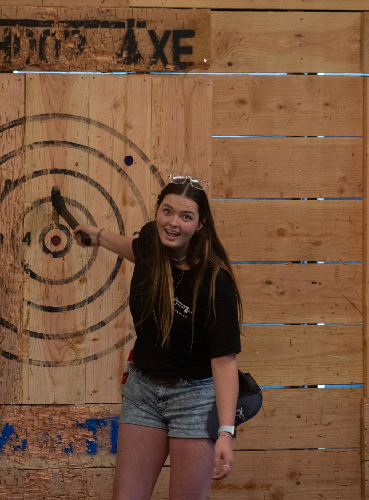 Guest releasing an axe toward the bullseye in an indoor Whoop Axe lane